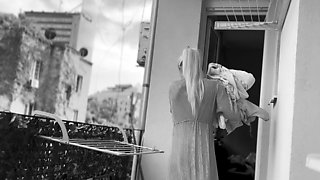 Naked chubby woman hangs out laundry on the balcony for